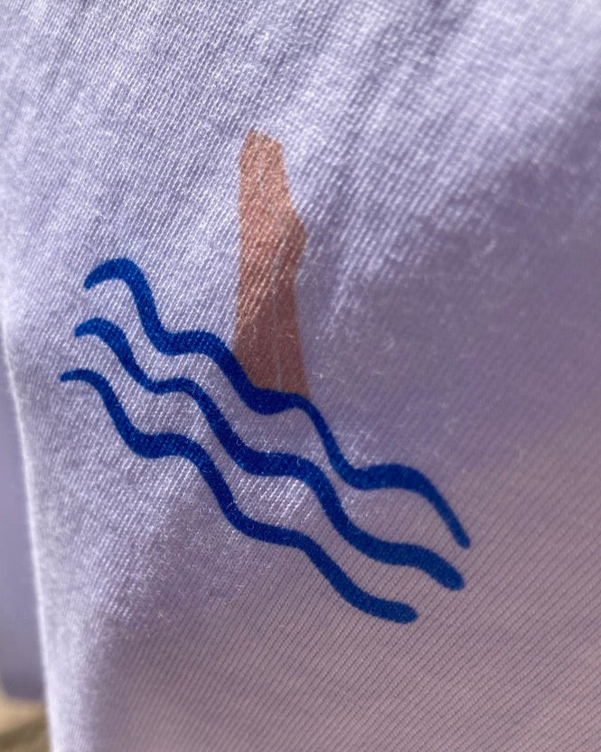 White shirt with blue wavy line design and brown stain on gray background