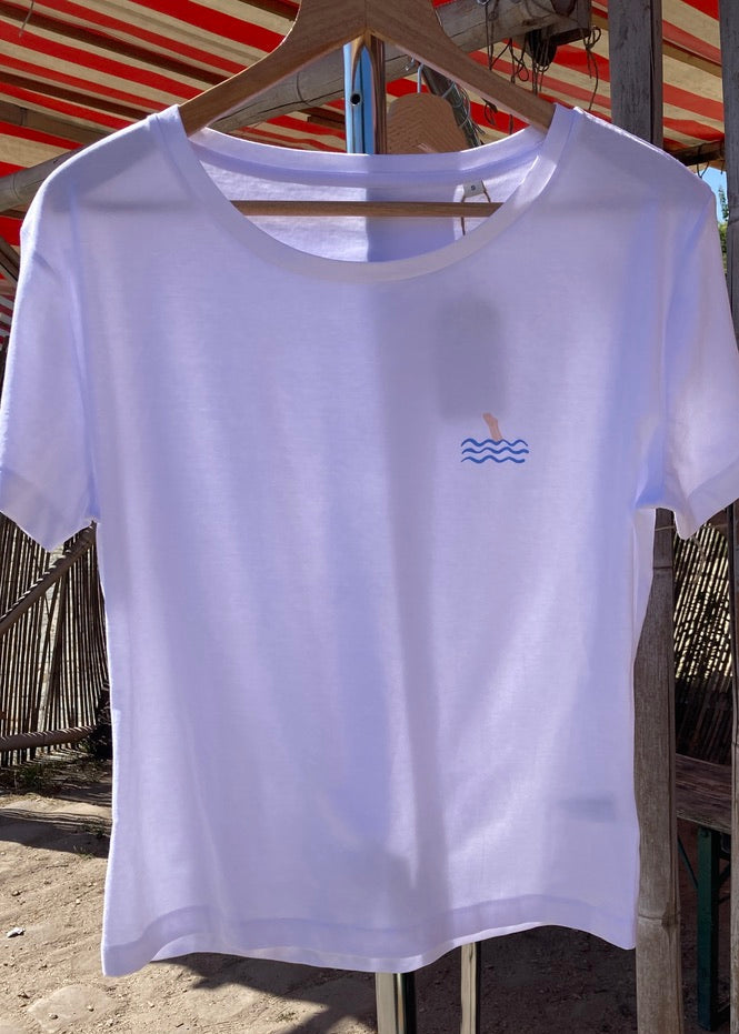 White t-shirt with a small logo on a hanger against a rustic background